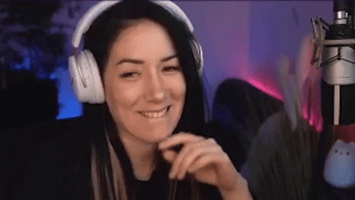 a girl with headphones on smiles as she plays a video game