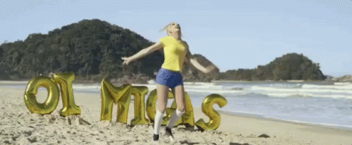 girl in shorts standing on the beach with large letters spelling mom