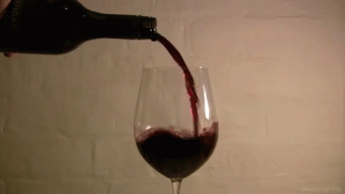 the glass of red wine is being poured