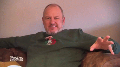 a man is sitting on the couch wearing a green shirt