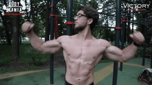 a man with a hairy chest standing in front of a set of climbing obstacles