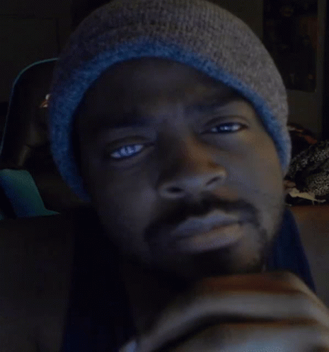 a black man wearing a beanie looks at the camera