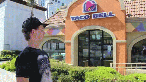 a woman standing outside of a taco bell store in the city