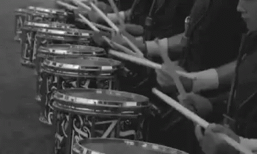 black and white po of men sitting in a row with drums