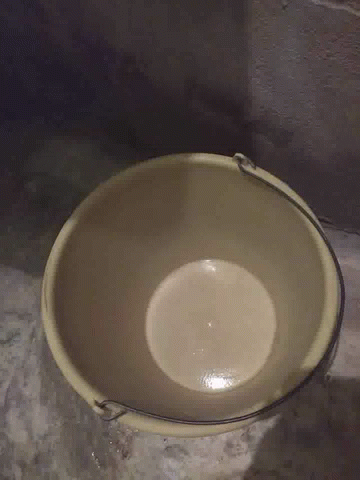 a white toilet sits inside of a small stone bucket