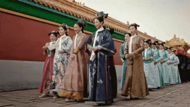 a group of women in korean style clothing standing next to a wall