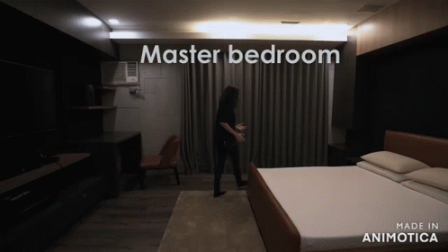 a woman standing in a room with a white bed