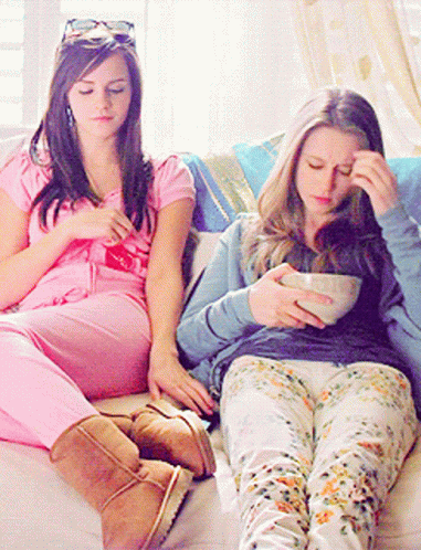 two girls on the couch playing with their phones