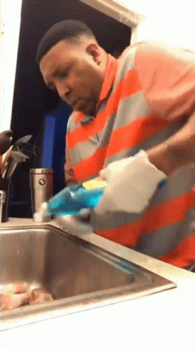 a man washing dishes in a kitchen on the sink