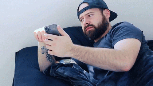 the bearded man is using a small electronic device