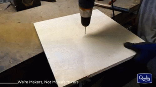 a person drilling with drill bit into plywood