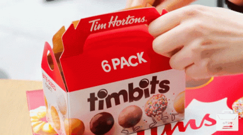 the hand holds a package of timbits wrapped in plastic