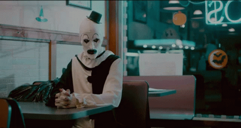 man dressed in a creepy mask seated at a table