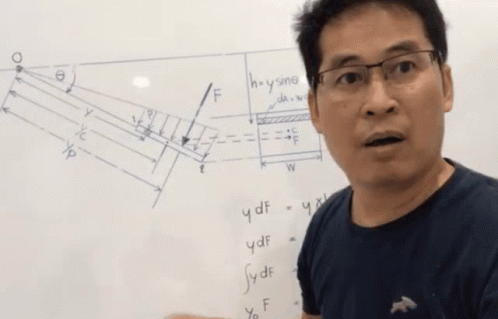 a guy with glasses is talking in front of a whiteboard