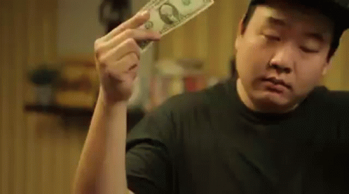 an asian man holding a dollar bill in his hand