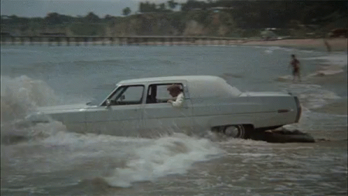 a white car traveling down a flooded beach