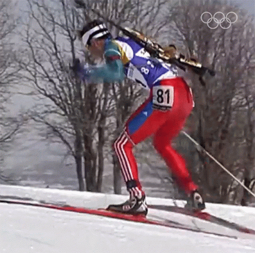 an olympic skier skiing down a mountain on the same slope as a speed sign