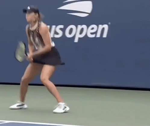 a woman in a tennis skirt and hat running to hit the tennis ball