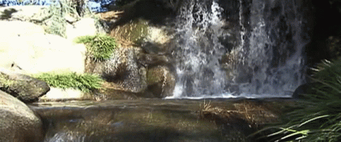 there is water falling down the waterfall and rocks