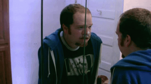 two men stand in front of the mirror in the bathroom