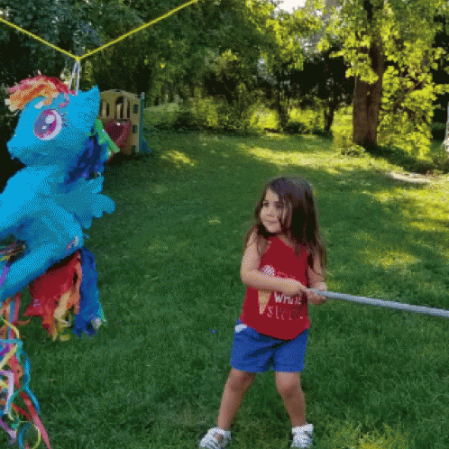 a  hitting a pinata outside in front of a dragon kite