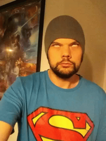the man in a superman t - shirt is wearing a black knit hat