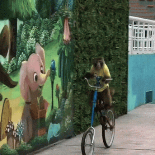 a monkey sits on a small bicycle next to a mural