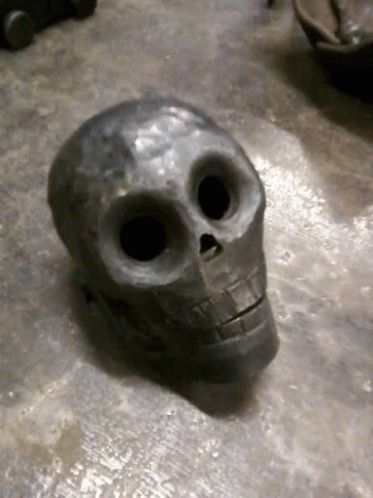 two small cast iron skulls that look to be placed on cement