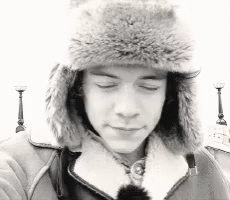 a boy in a fur hat looking at his cellphone