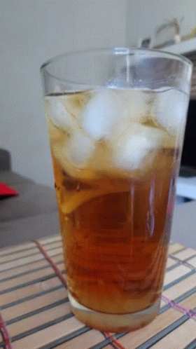 an unidentifiable drink with ice inside sits on the table
