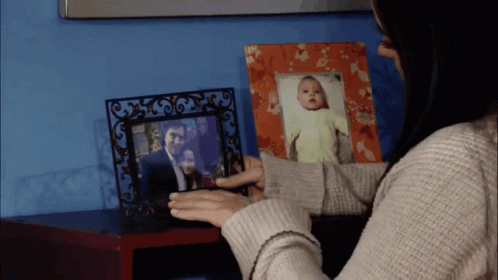 a woman holding a picture next to a small po