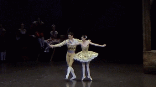 a man and a woman in ballet outfits standing on one leg