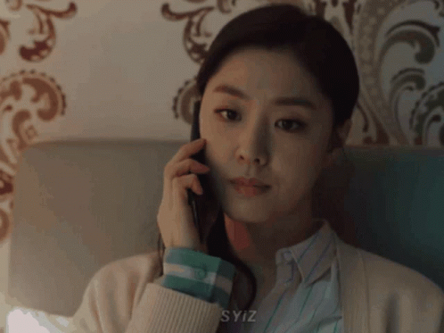 a young asian woman in a beige sweater is talking on a phone