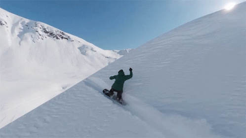 man snowboarding down side of a snowy mountain