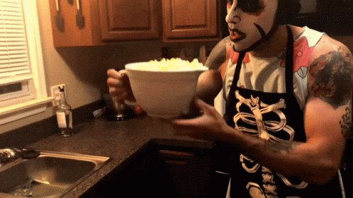 a person with a scary face standing in a kitchen with a bowl