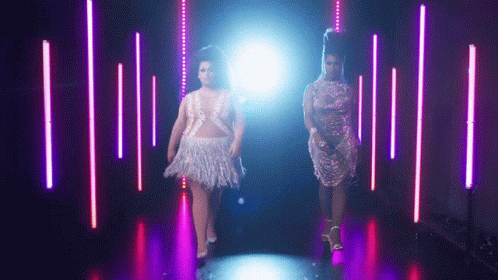 two women are walking down the runway while the light is shining