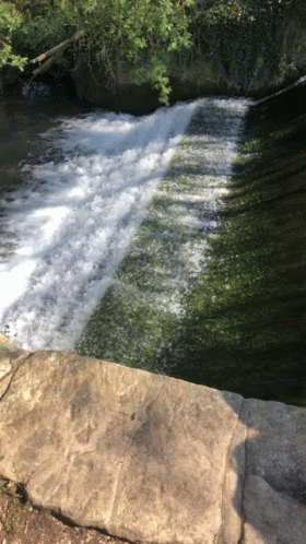 a stream flowing down a mountain river by a rock