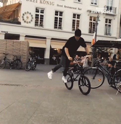 a man doing tricks on some bikes in the middle of a city street