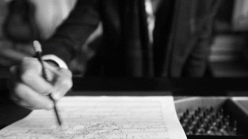 a person sitting at a table writing on paper