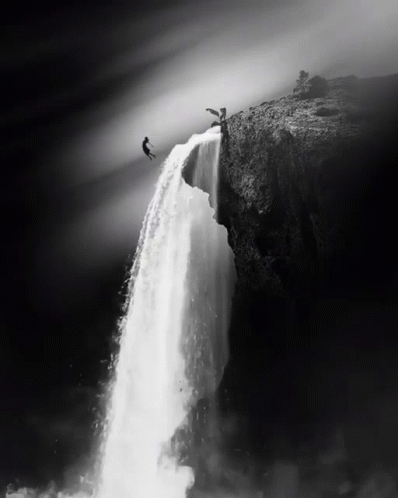 a man jumps off a waterfall into a lake below