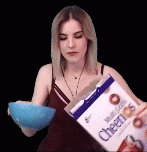 a woman holding a box of cereal over a bowl