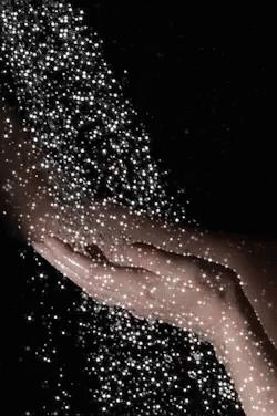 a person's hand holds glittery sparkle in the dark