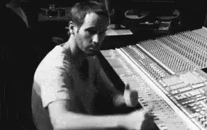the man in the white shirt is sitting at a sound mixing board