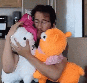 a person hugging two different stuffed animals in a kitchen