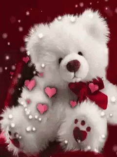 the white teddy bear with purple hearts is posed