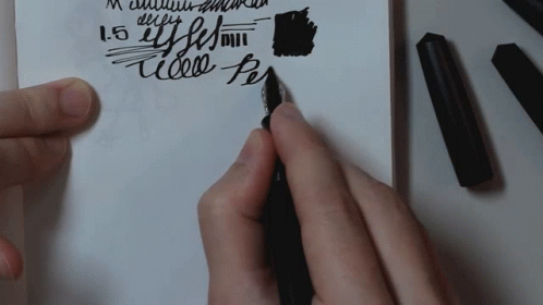 two hands are drawing with black marker and writing on white paper