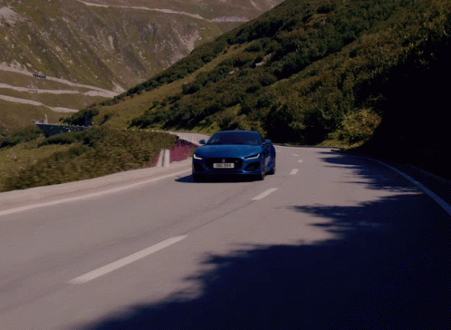 the orange sports car drives along a mountain road