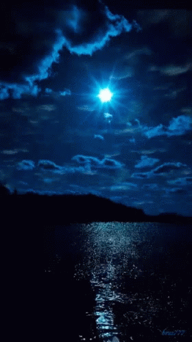 an evening view with the moon, clouds and water reflecting bright from it