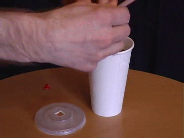hand holding a small plastic cup on a round table