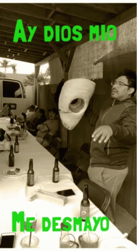 a man is sticking a mask in his face as the others around him drink and eat